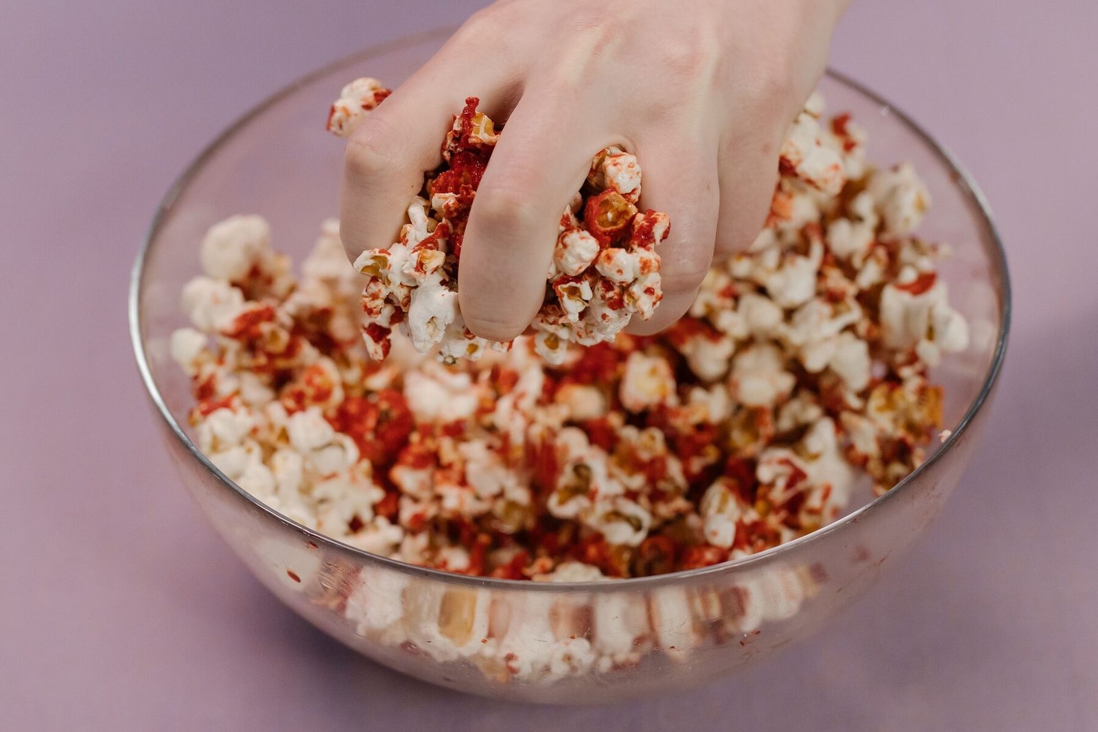 A hand reaching into a bowl of popcorn