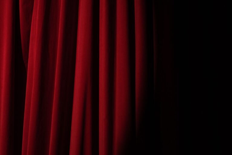 A dramatic red theater curtain, lit from the side
