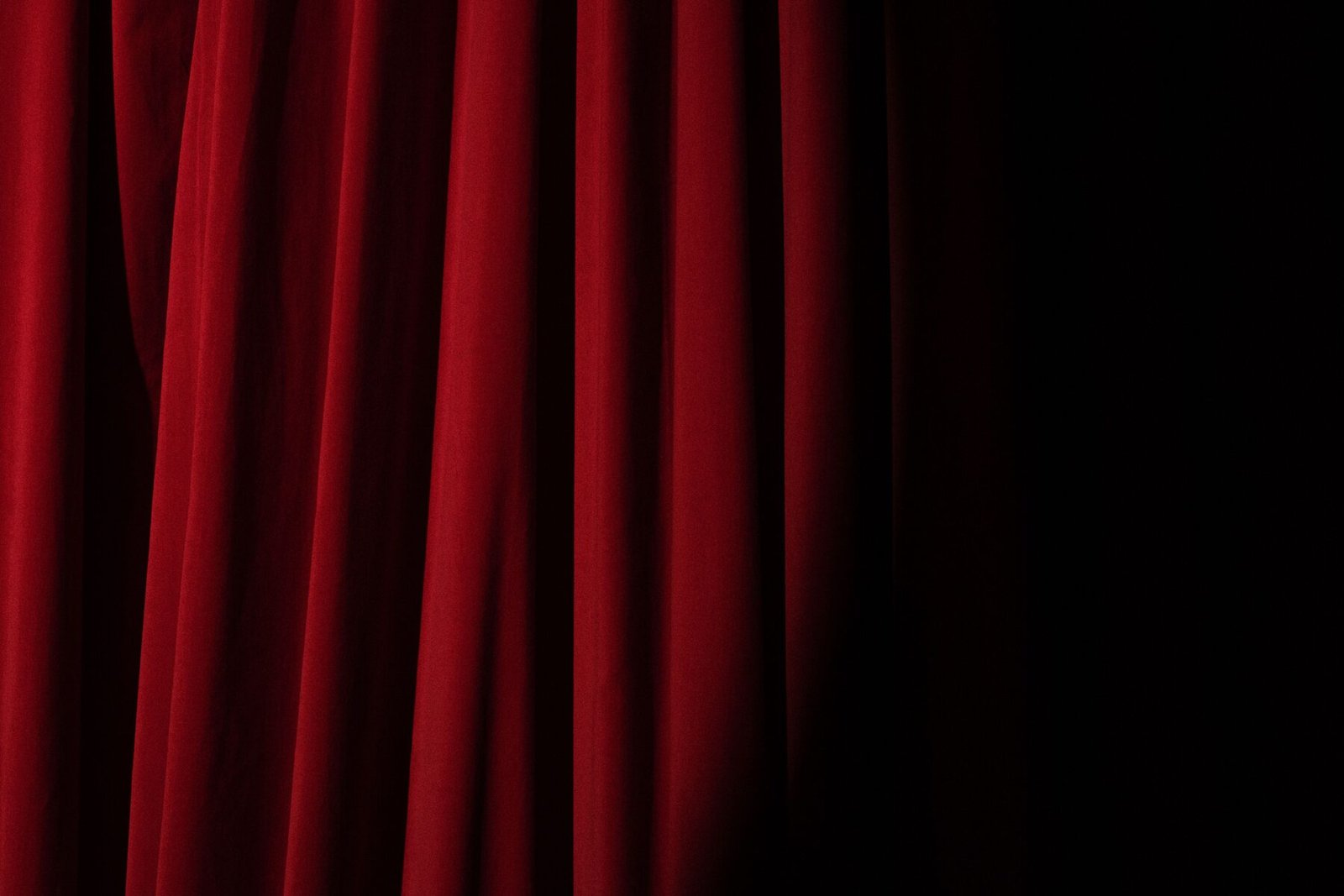 A dramatic red theater curtain, lit from the side